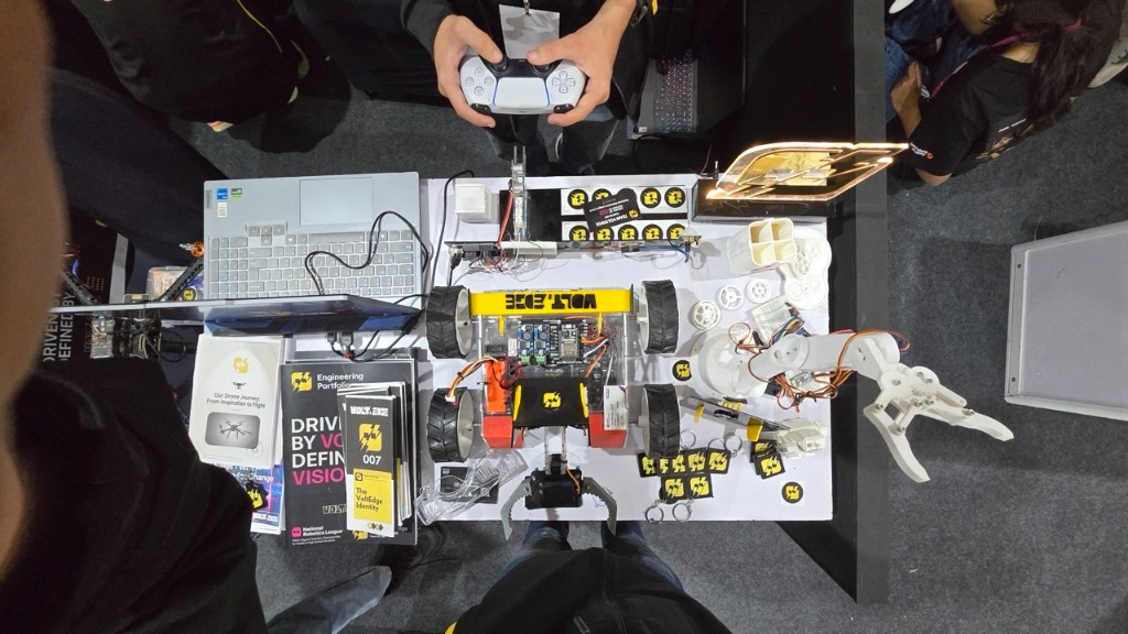 Top-down view of EdgeBot chassis, 3D arm, PS5 controller, and pit table